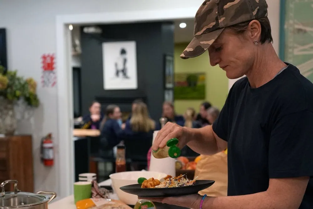 Member of a girls school hockey team preparing a meal while staying at Kiwiesque.