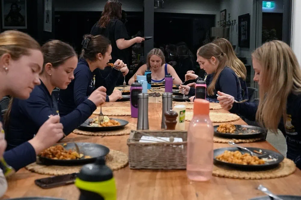School girls hockey team enjoying a meal together while staying at Kiwiesque.