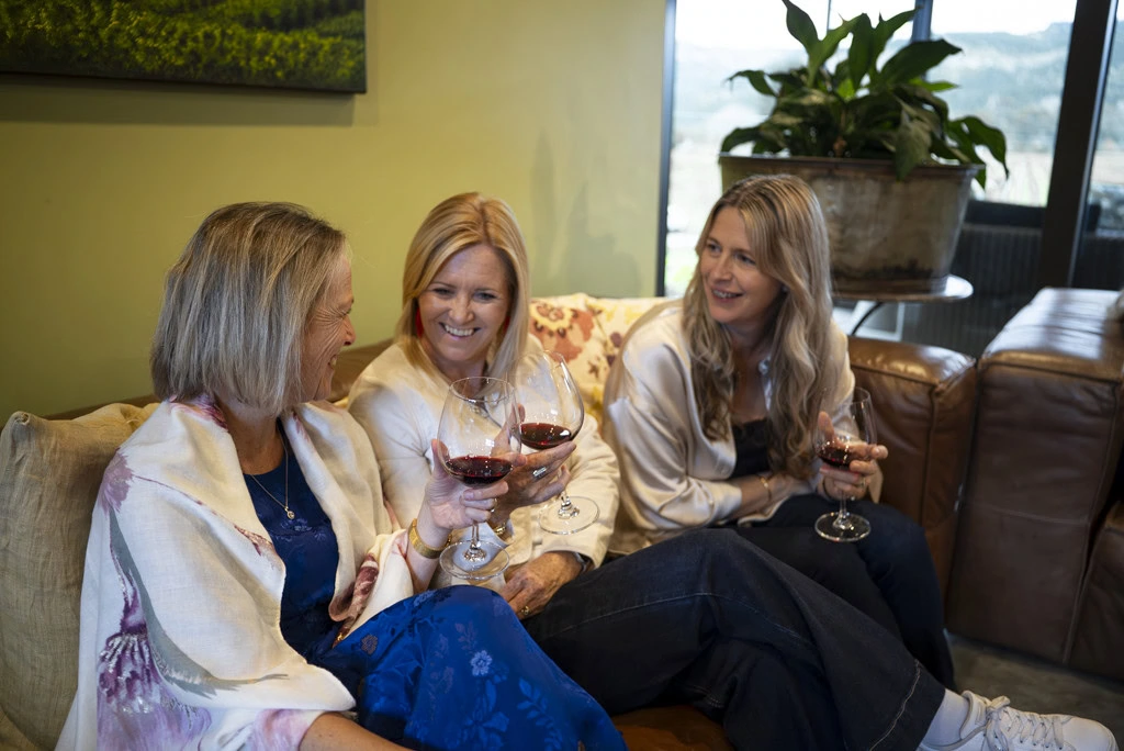 Three woman guests in conversation while holding wine glasses at a Kiwiesque Winter Food and Wine Experience