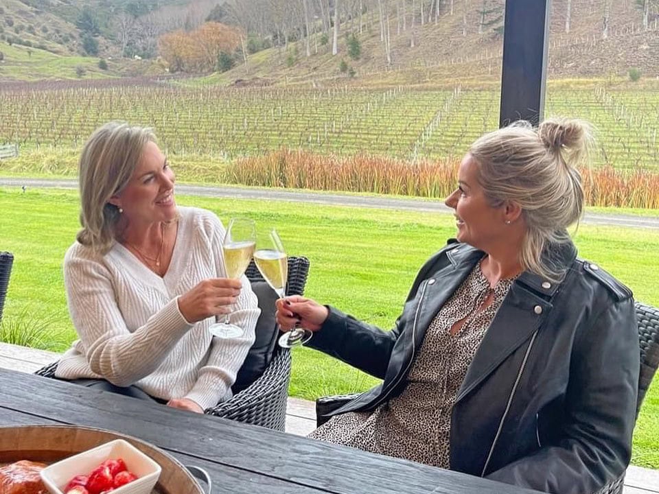 Two woman enjoying a glass of wine outside the Vineyard Villa at Kiwiesque